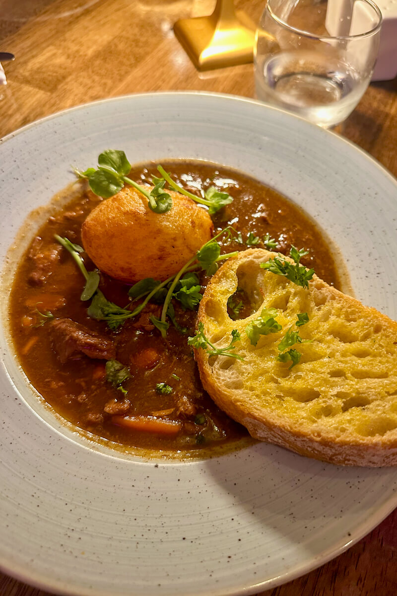 Overhead view of Irish beef stew with a potato and slice of bread.