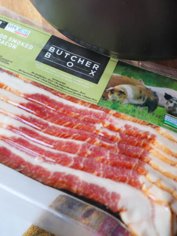 Butcher Box bacon in the clear packaging on a surface next to a black ceramic pot