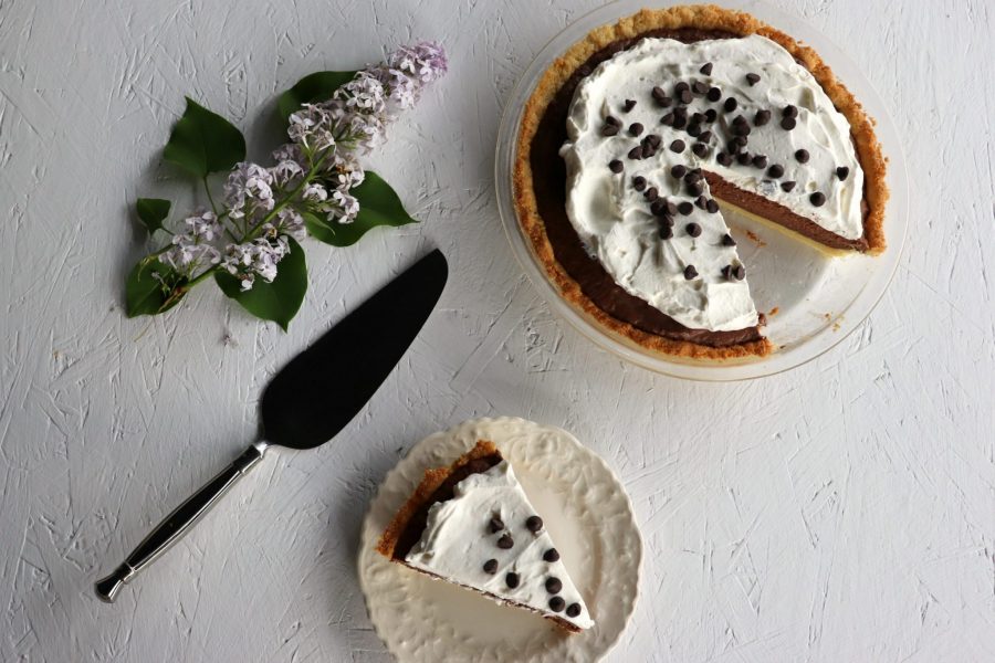 Overhead low carb chocolate pie with piece cut out on a plate, serving piece, lilac
