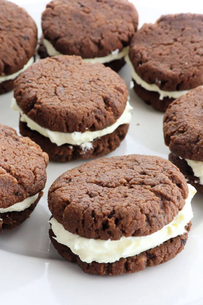 Delicious keto chocolate sandwich cookies on a plate are the perfect gluten-free snack. A cross between a keto oreo and a keto whoopie pie, these sugar-free treats are a family favorite. #ketorecipes #lowcarbcookies