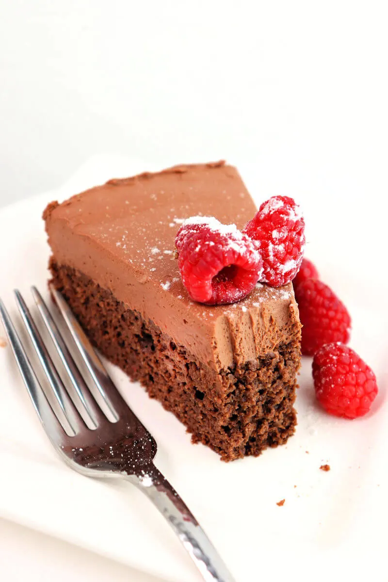 Bite out of a piece of keto chocolate mousse cake with raspberries.