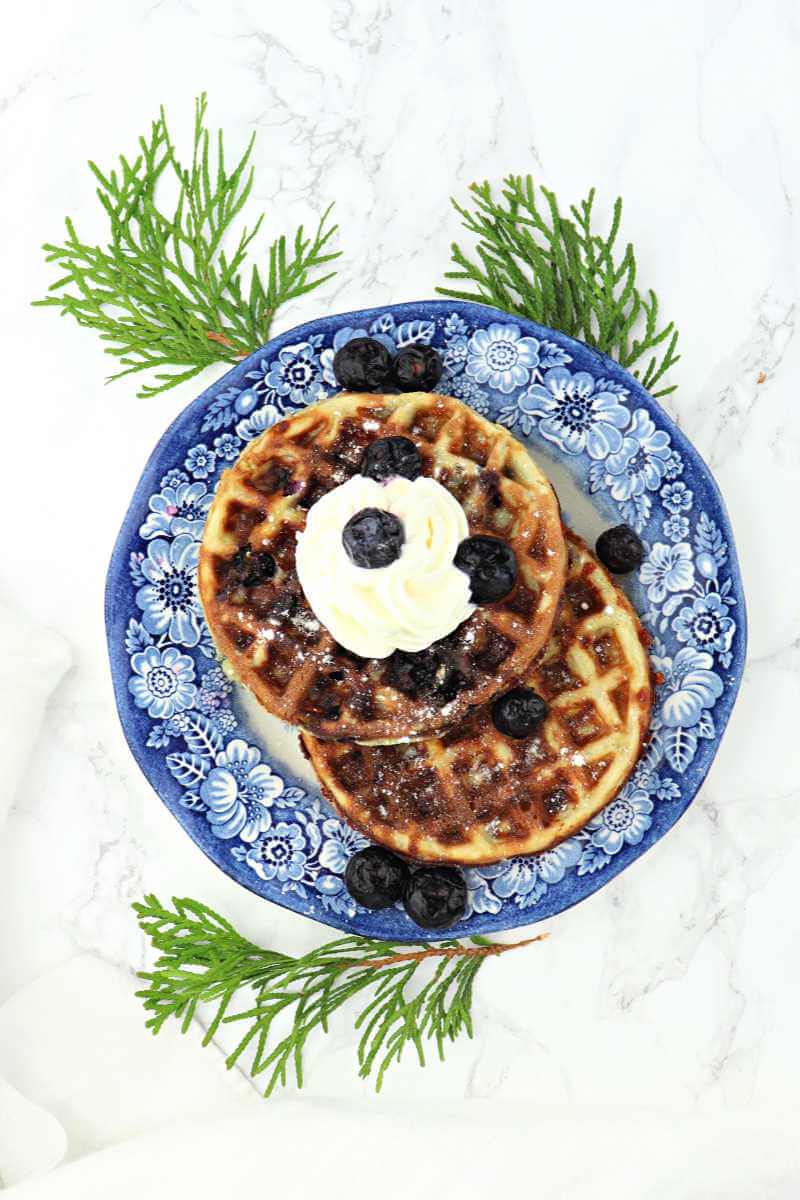 Keto Blueberry Chaffles are filled with traditional morning flavors! Low carb, super-easy to make and delicious, you won't believe they're sugar-free and gluten-free. #chaffles #blueberrychaffles #ketobreakfast