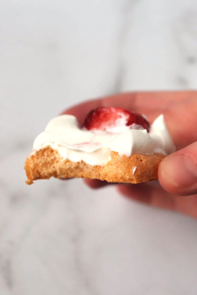 Bite out of a strawberry keto meringue cookie. #ketomeringuecookies #ketodesserts #ketorecipes
