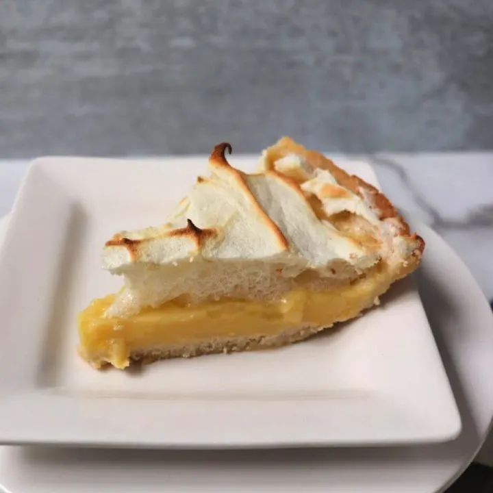 Piece of keto lemon meringue pie. Super-tart yet sweet with that delicious meringue topping. #ketopie #ketodessertrecipes