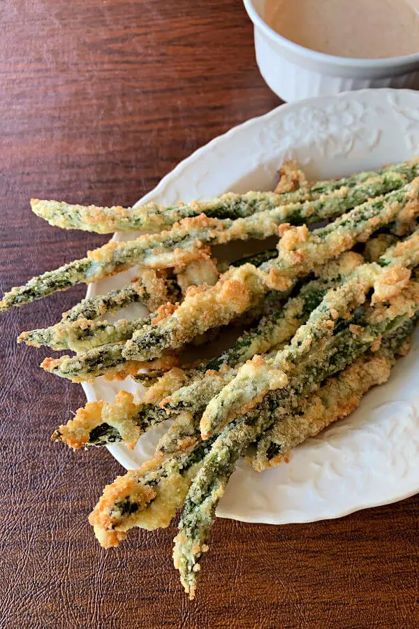 Crispy keto baked asparagus fries coated with parmesan and pork rind powder. Served with a flavorful spicy lemon garlic dip.