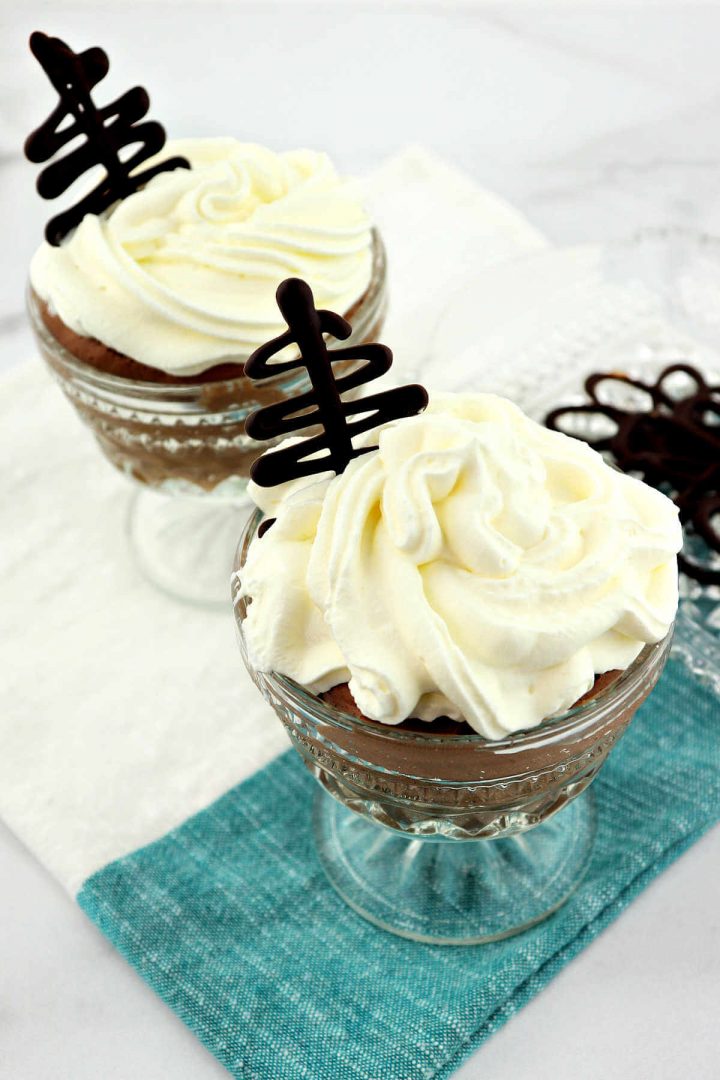 Two dishes of keto chocolate mousse with sugar-free whipped cream and chocolate decoration.