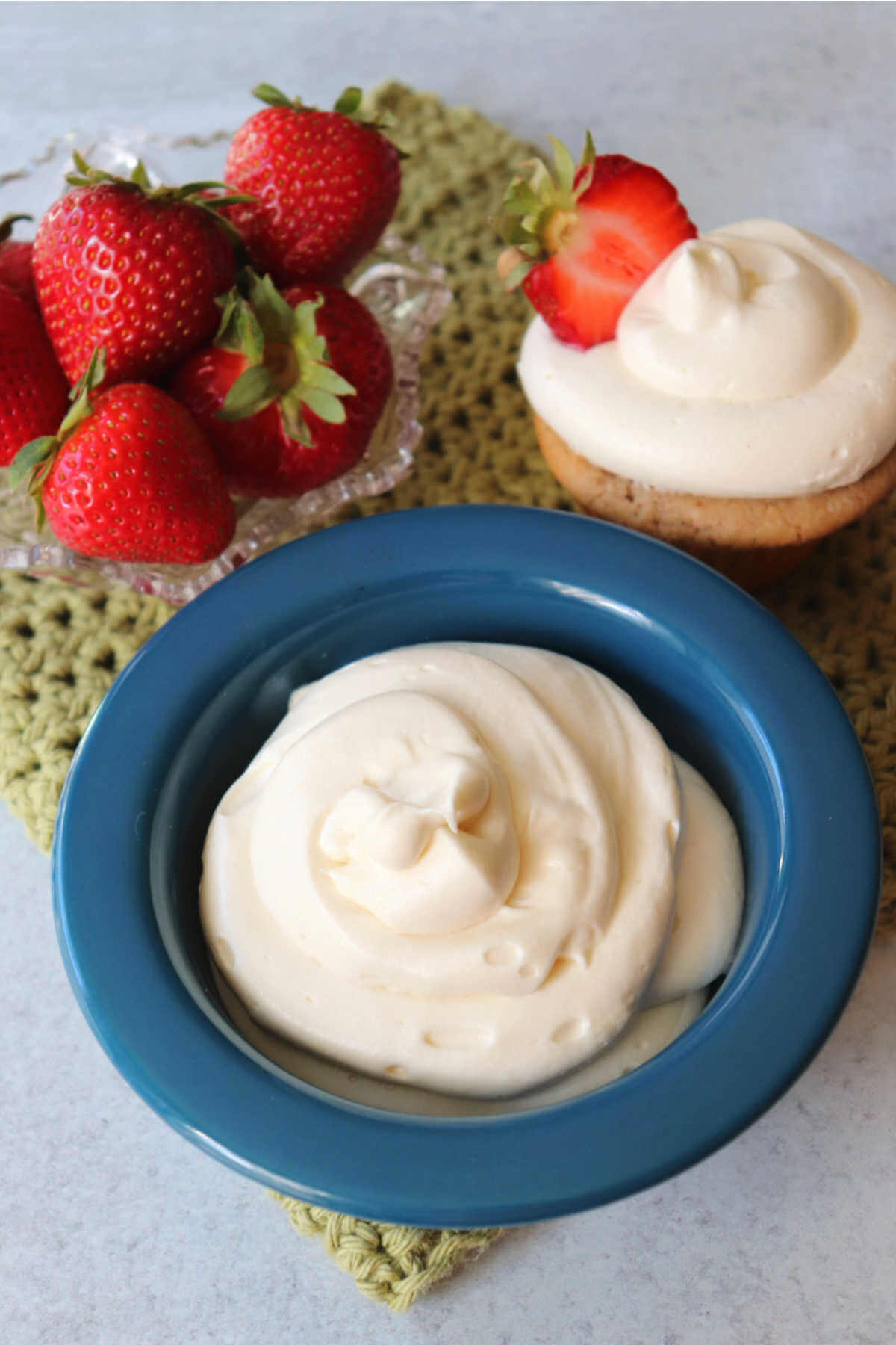 Bowl of sugar-free cream cheese frosting and a keto strawberry cupcake.