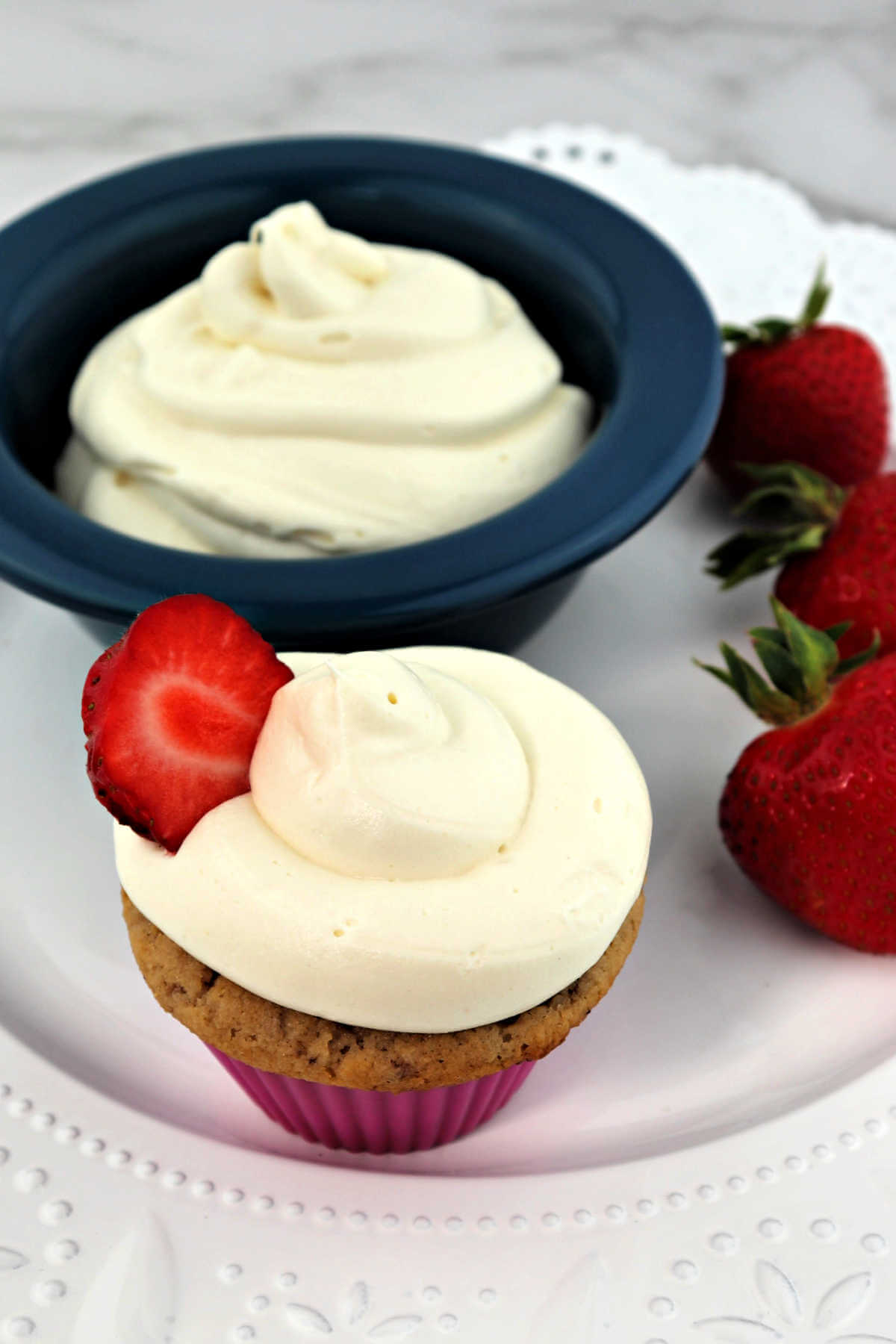 Keto cream cheese frosting on a strawberry cupcake and in a bowl.