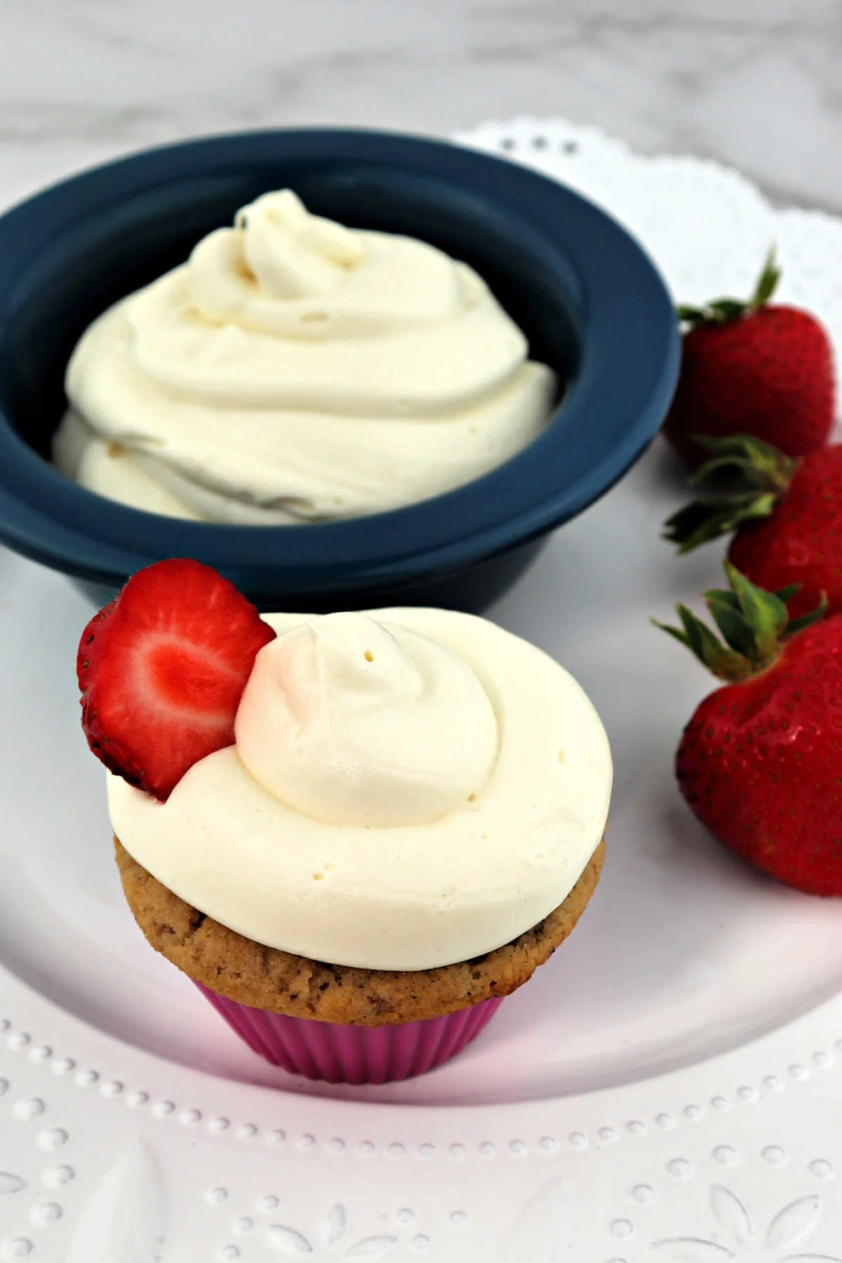 Keto cream cheese frosting on a strawberry cupcake and in a bowl.