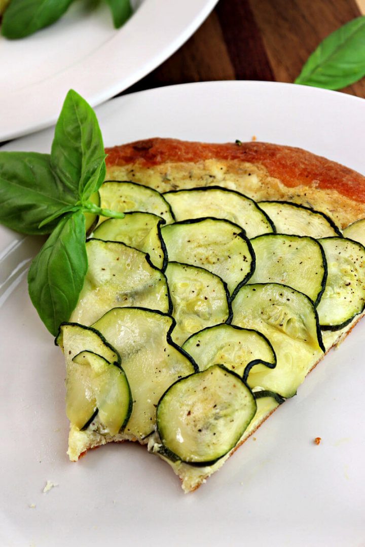 Bite out of a piece of keto zucchini tart pizza