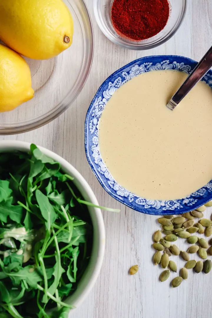 Keto Tahini dressing in a bowl with ingredients around