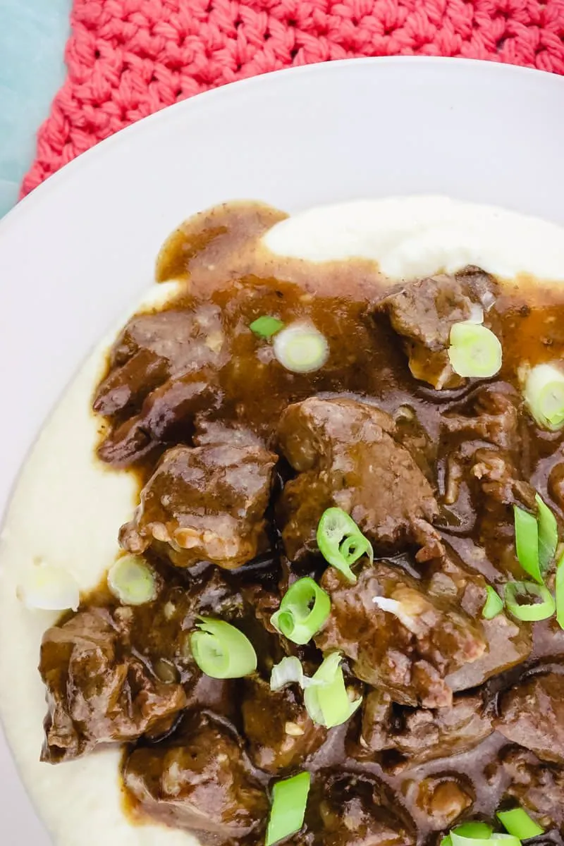 Easy keto beef tips with gravy on a plate with cauliflower mashed potatoes