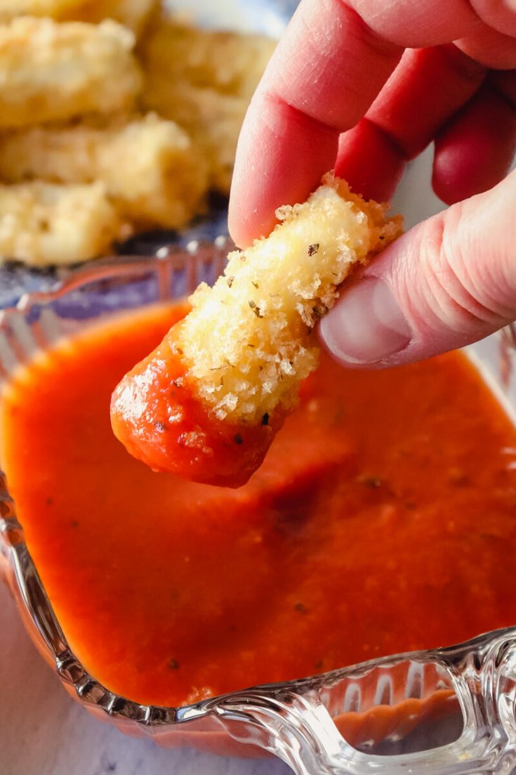 Keto mozzarella stick dipped in marinara sauce