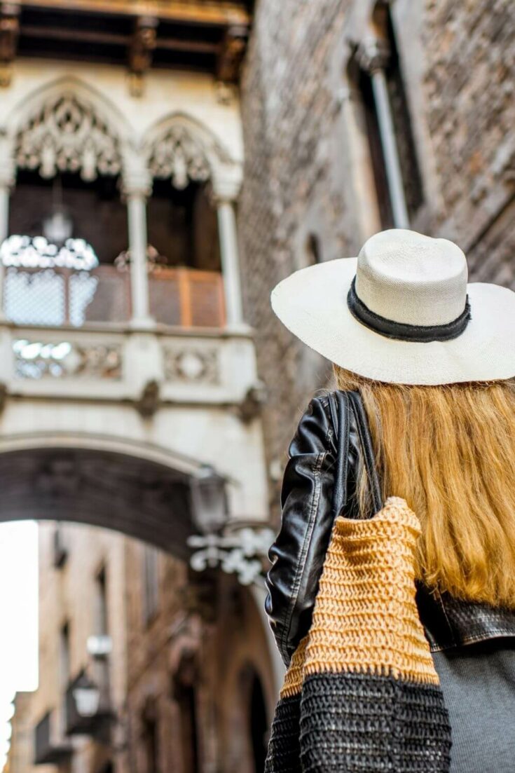 A woman in a white hat looking up at the Spanish bridge of sighs