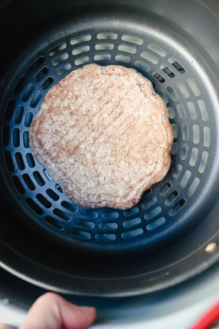 Overhead view of a frozen burger in an air fryer basket