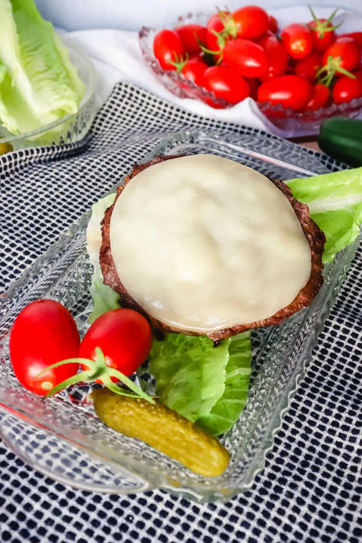 Burger on a plate with lettuce and tomatoes, pickles