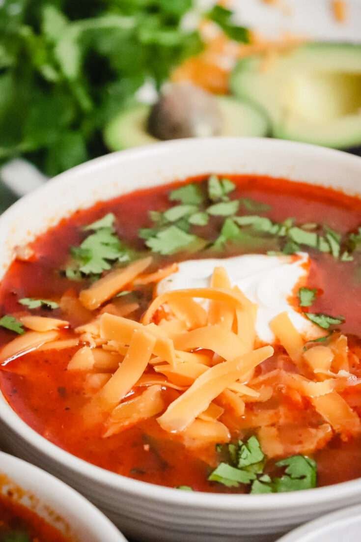 Bowl of keto chicken enchilada soup with sour cream and cheese
