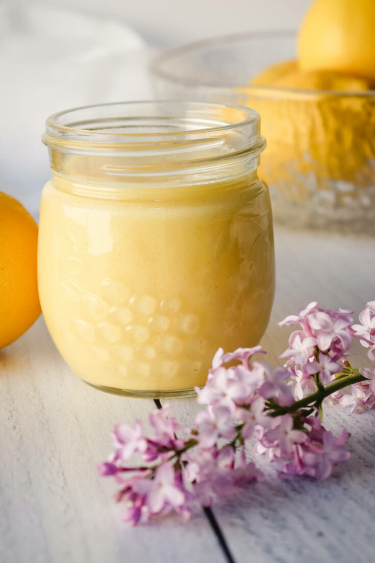 Jar of low carb lemon curd and a sprig of lilacs