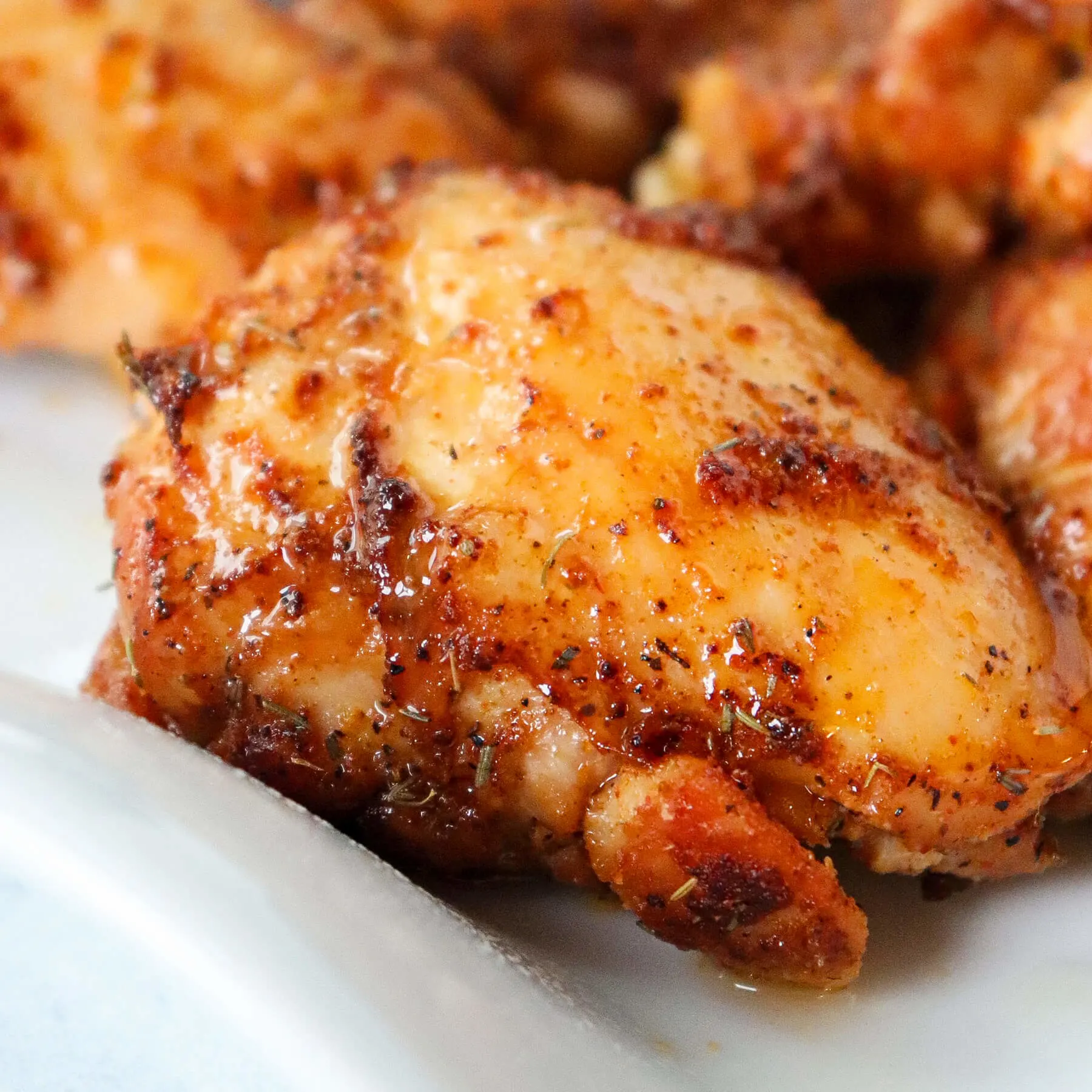 Air fryer boneless skinless chicken thigh on a white plate.