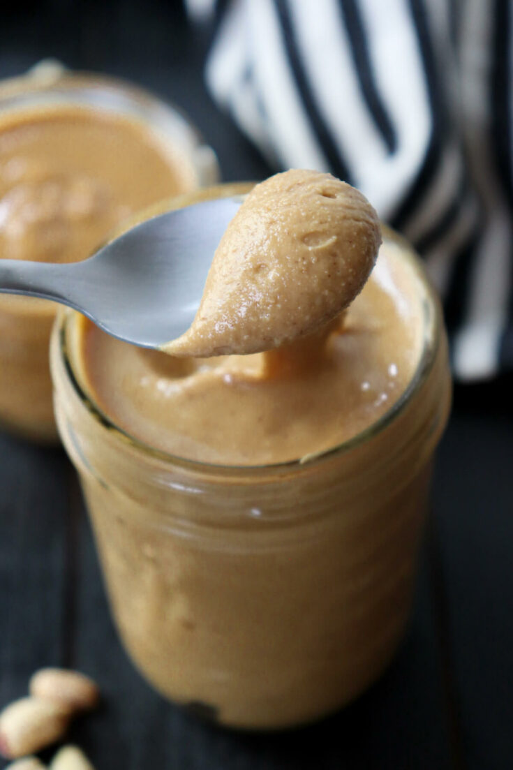Spoon of homemade peanut butter in a jar