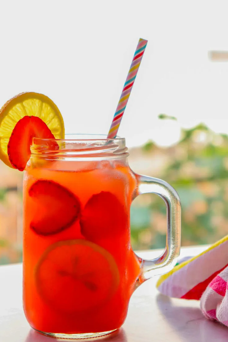 Glass of ketogenic lemonade with strawberries in front of a window