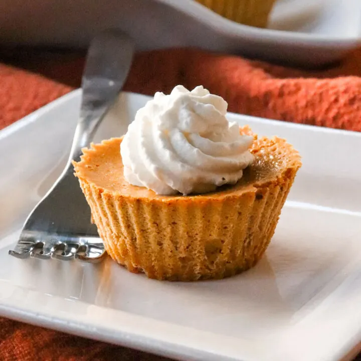 One mini keto pumpkin pie on a white plate with a fork
