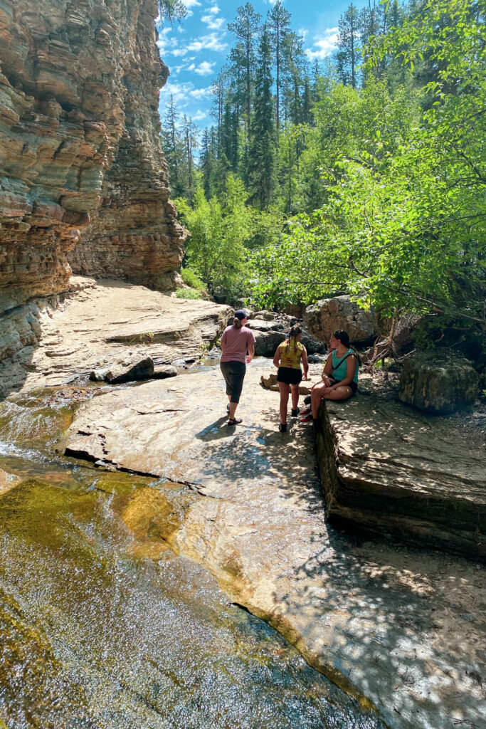 Woman and girls hiking on rocks next to a stream