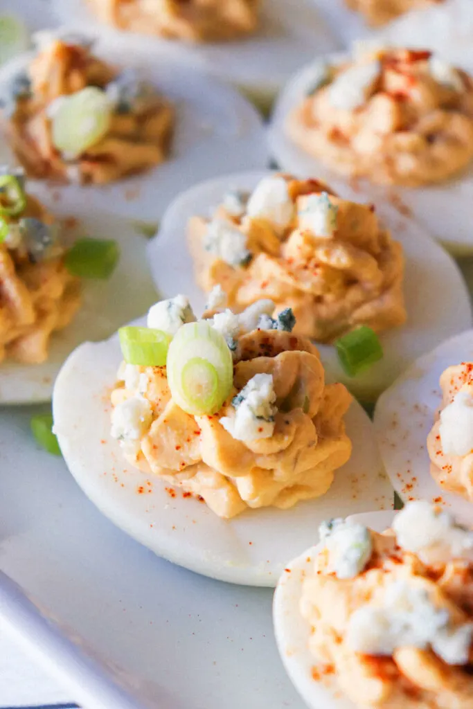 Deviled eggs on a white plate with toppings