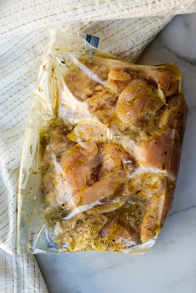 A zipper bag filled with chicken and a Greek style marinade