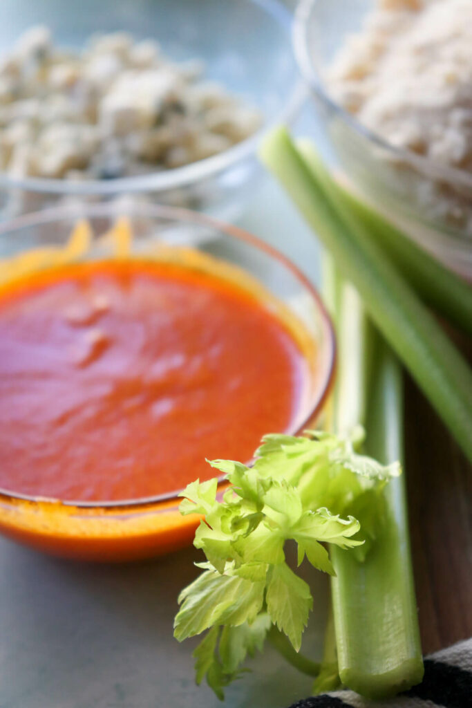 Buffalo sauce in a glass bowl with celery