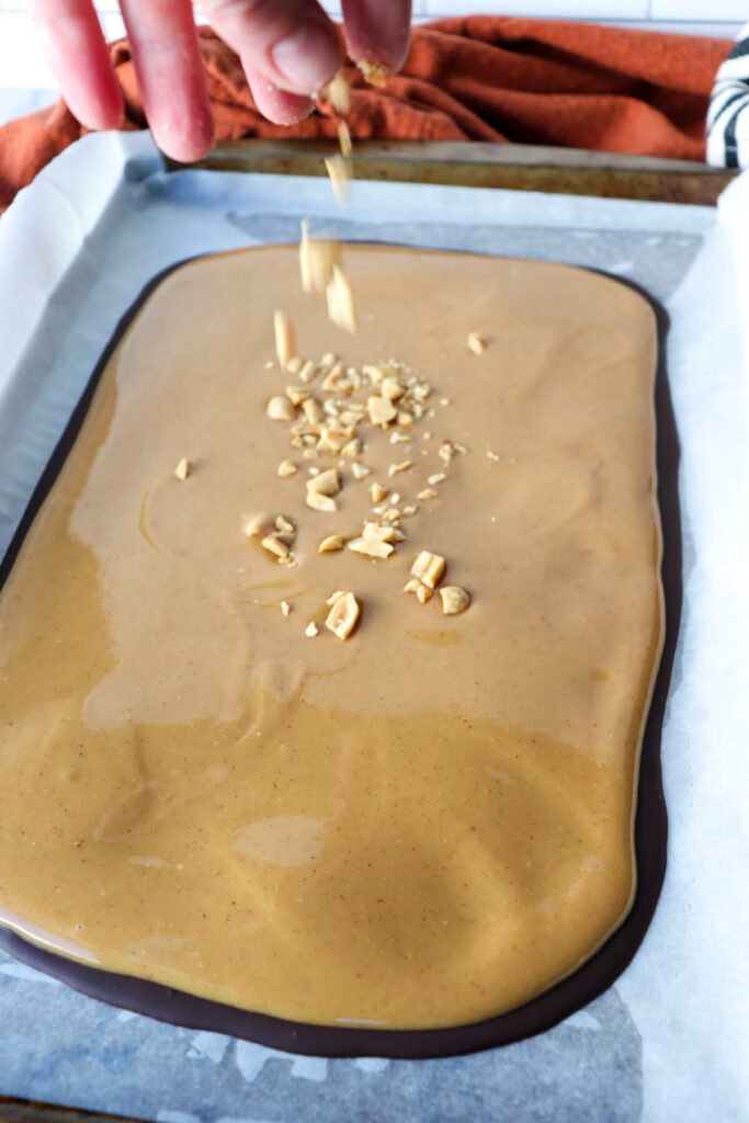 Low carb peanut butter bark being sprinkled with peanuts