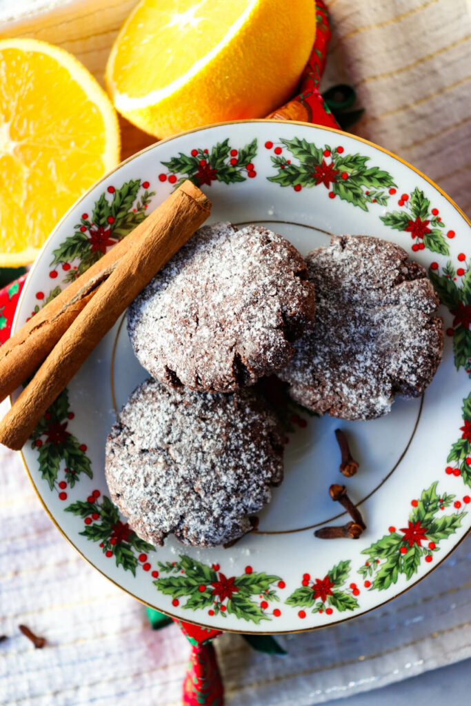 Overhead view of three keto crinkle cookies on a festive plate with cinnamon sticks next to an orange