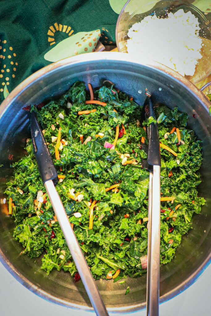 Overhead view of a metal salad bowl filled with keto kale salad and tongs