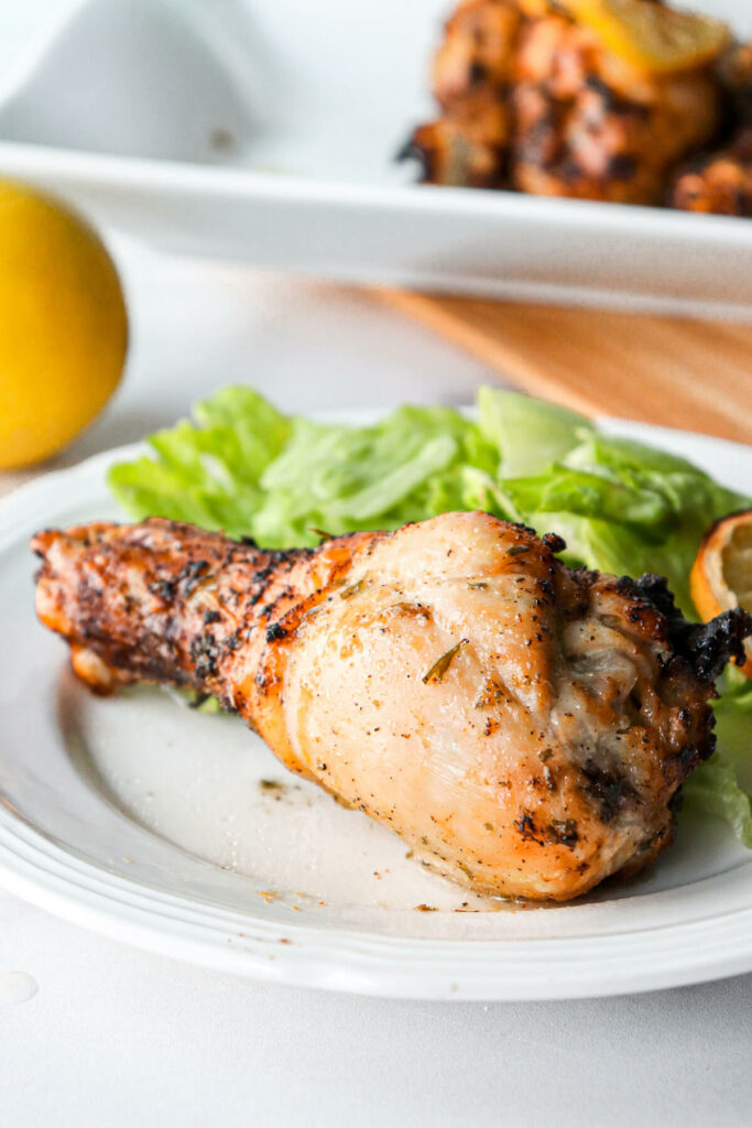 Air fryer chicken leg on a white plate with lettuce