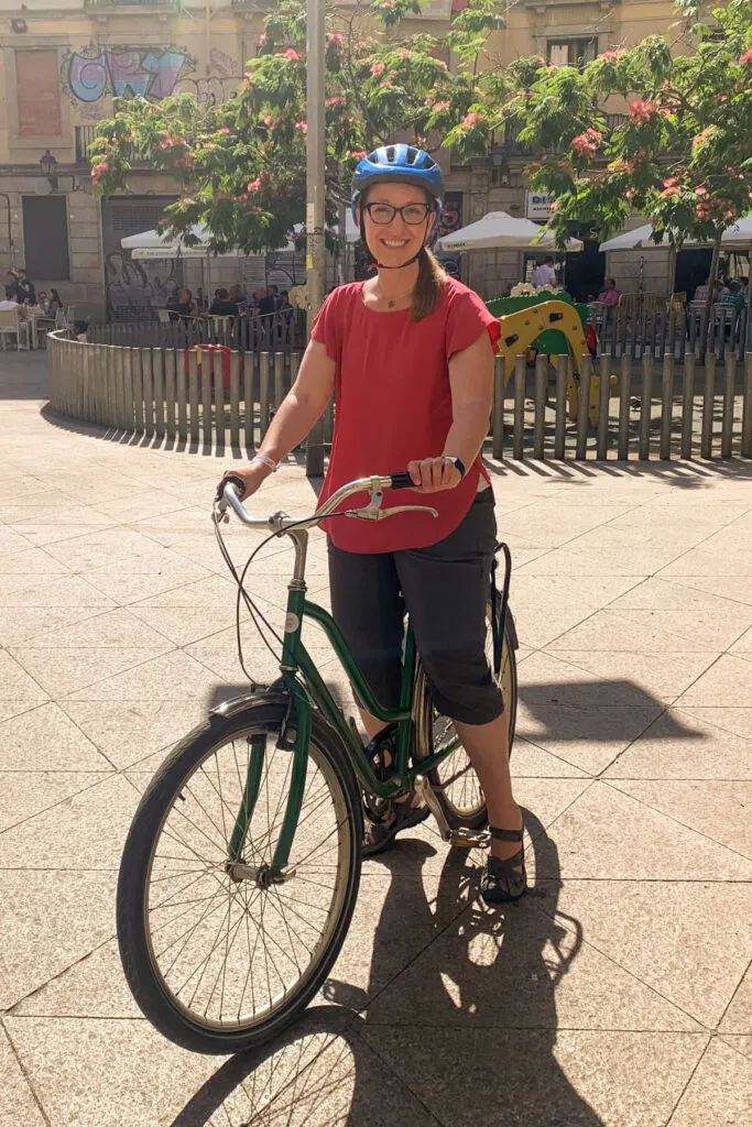 Woman in a pink blouse on a green bike in Barcelona