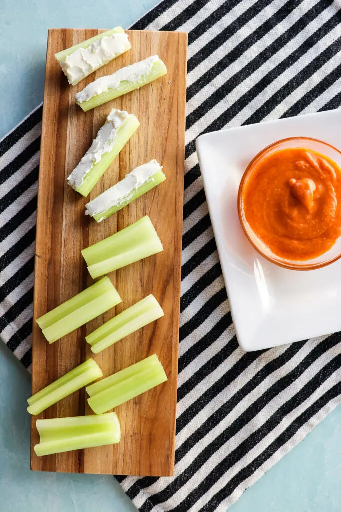 Overhead view of celery stuffed with cream cheese and a side of Buffalo sauce