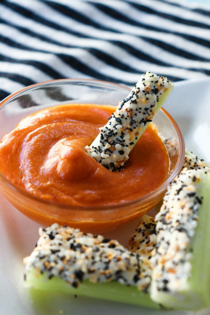 Easy keto celery snacks with keto Buffalo sauce for dipping on a white plate