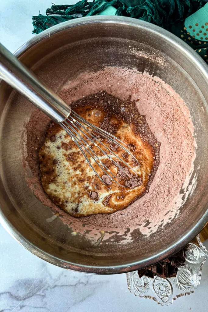 Overhead view of a bowl whisking keto brownies dry ingredients into wet