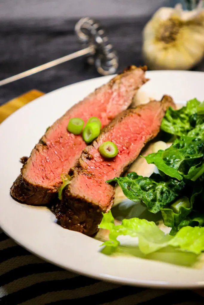 Two slices of air fryer flank steak on a white plate