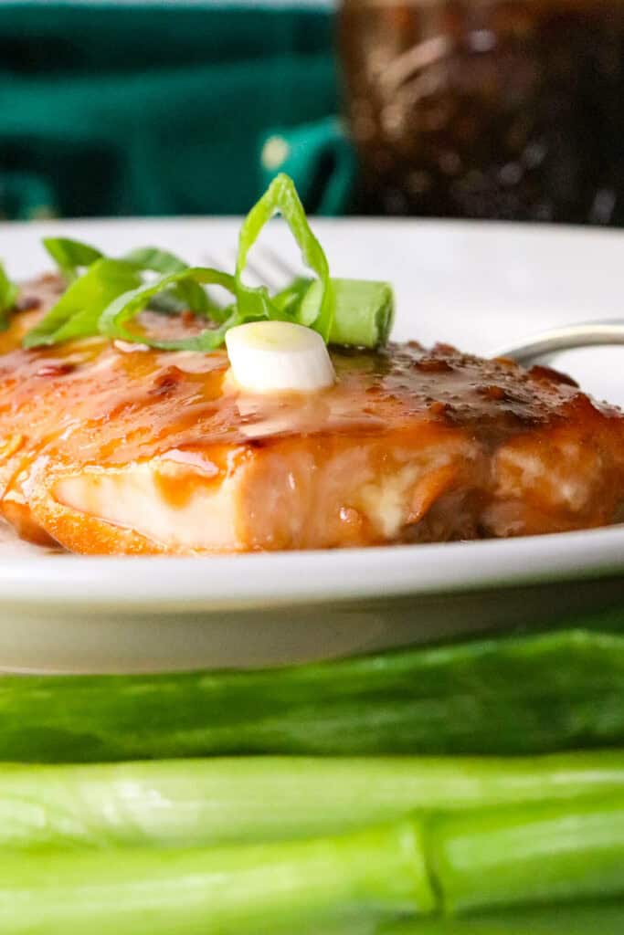 A serving of air fryer salmon teriyaki on a white plate, front closeup view