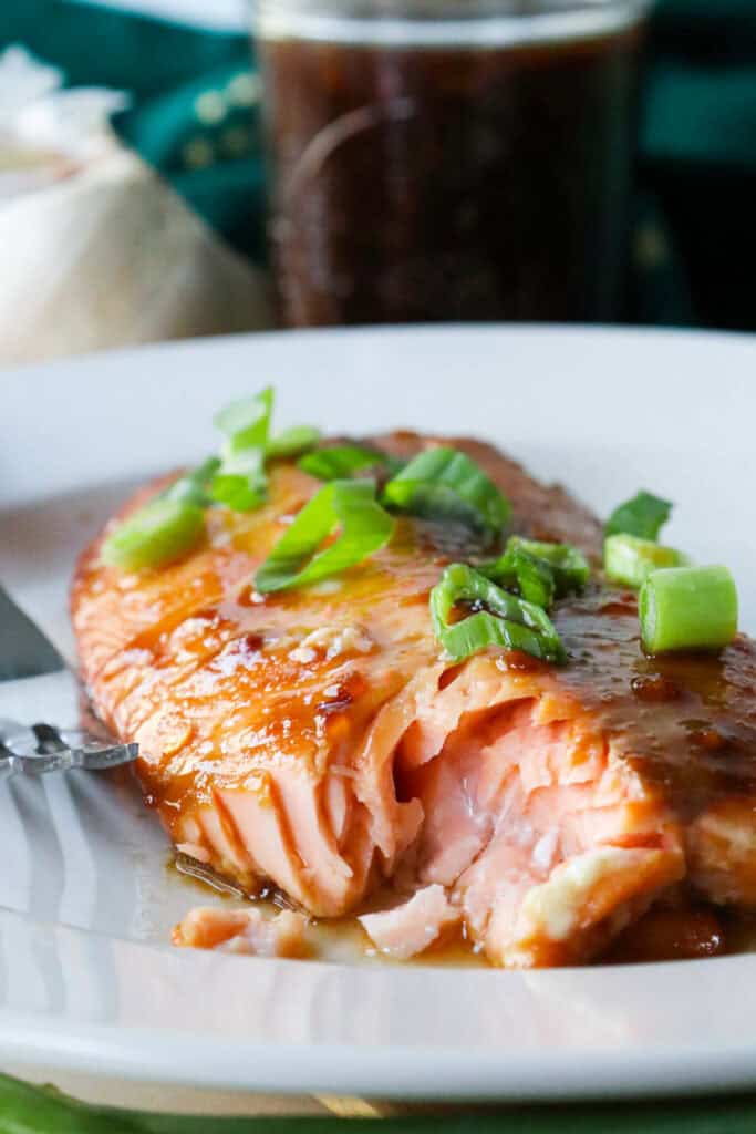 Air fryer teriyaki salmon on a white plate with a bit taken out