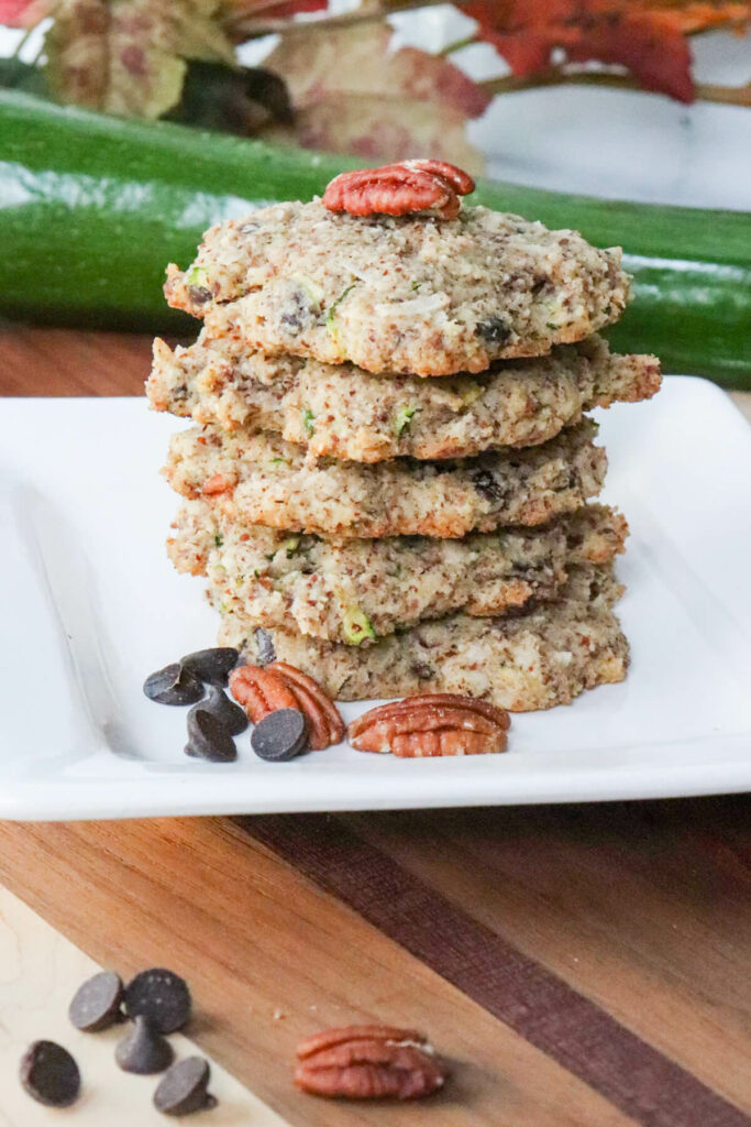 A stack of five keto chocolate chip zucchini cookies with a pecan on top.