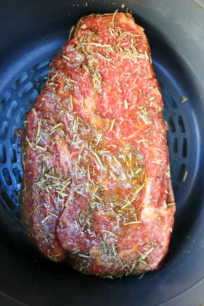 Raw beef roast with the coating in the air fryer basket