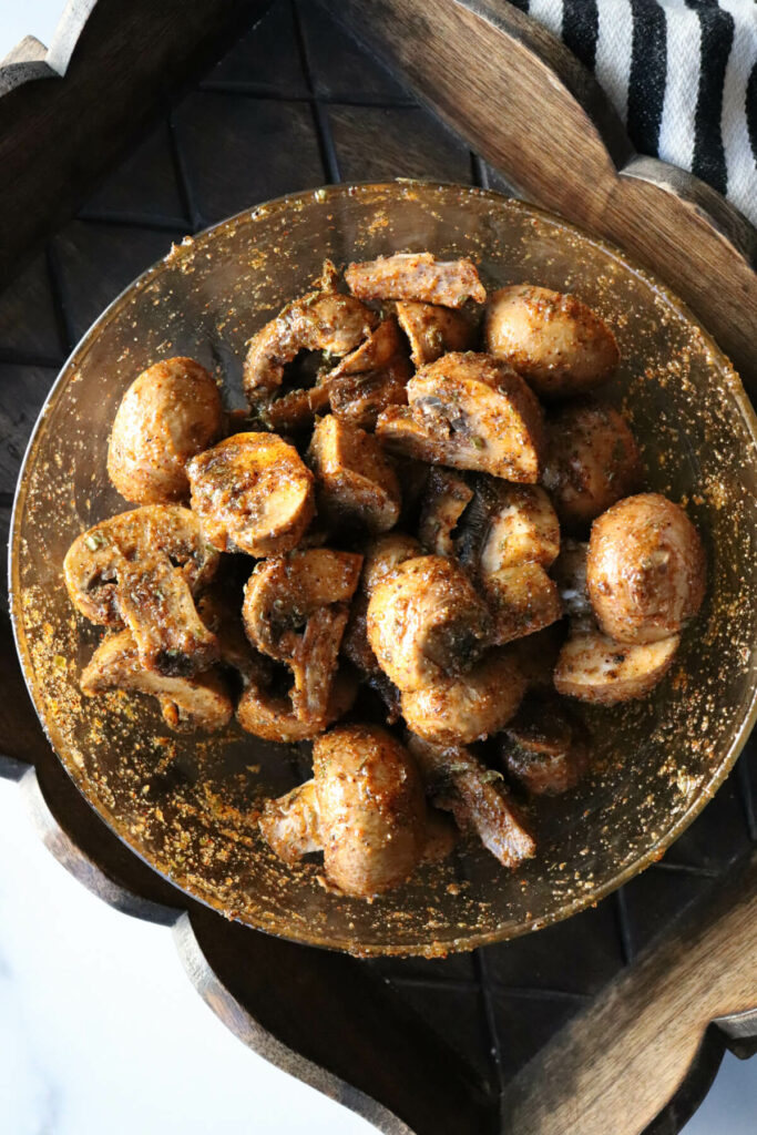 Overhead view of a bowl of mushroom coated in oil and spices