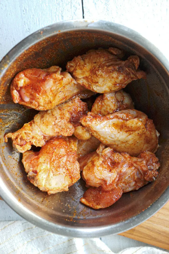Overhead view of chicken wings in a metal bowl with marinade