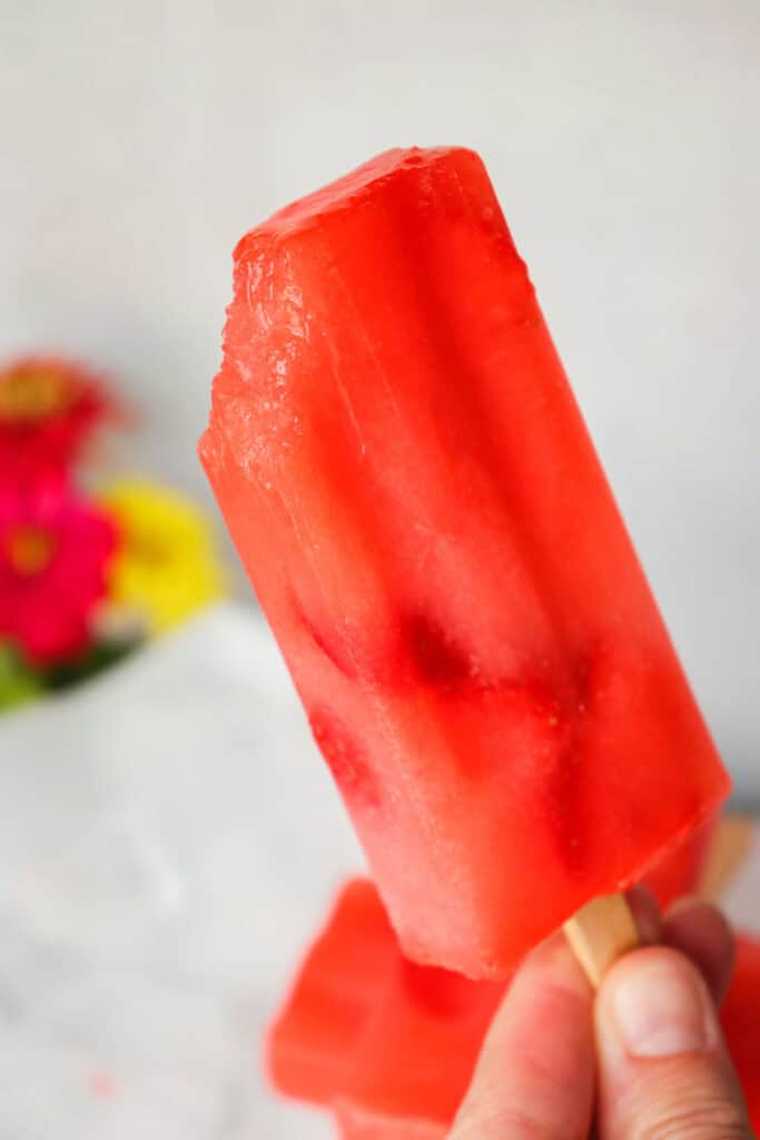 A bite taken out of a sugar free strawberry lemonade keto popsicle