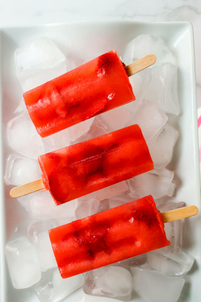 Overhead view of red sugar free popsicles, keto strawberry lemonade on ice