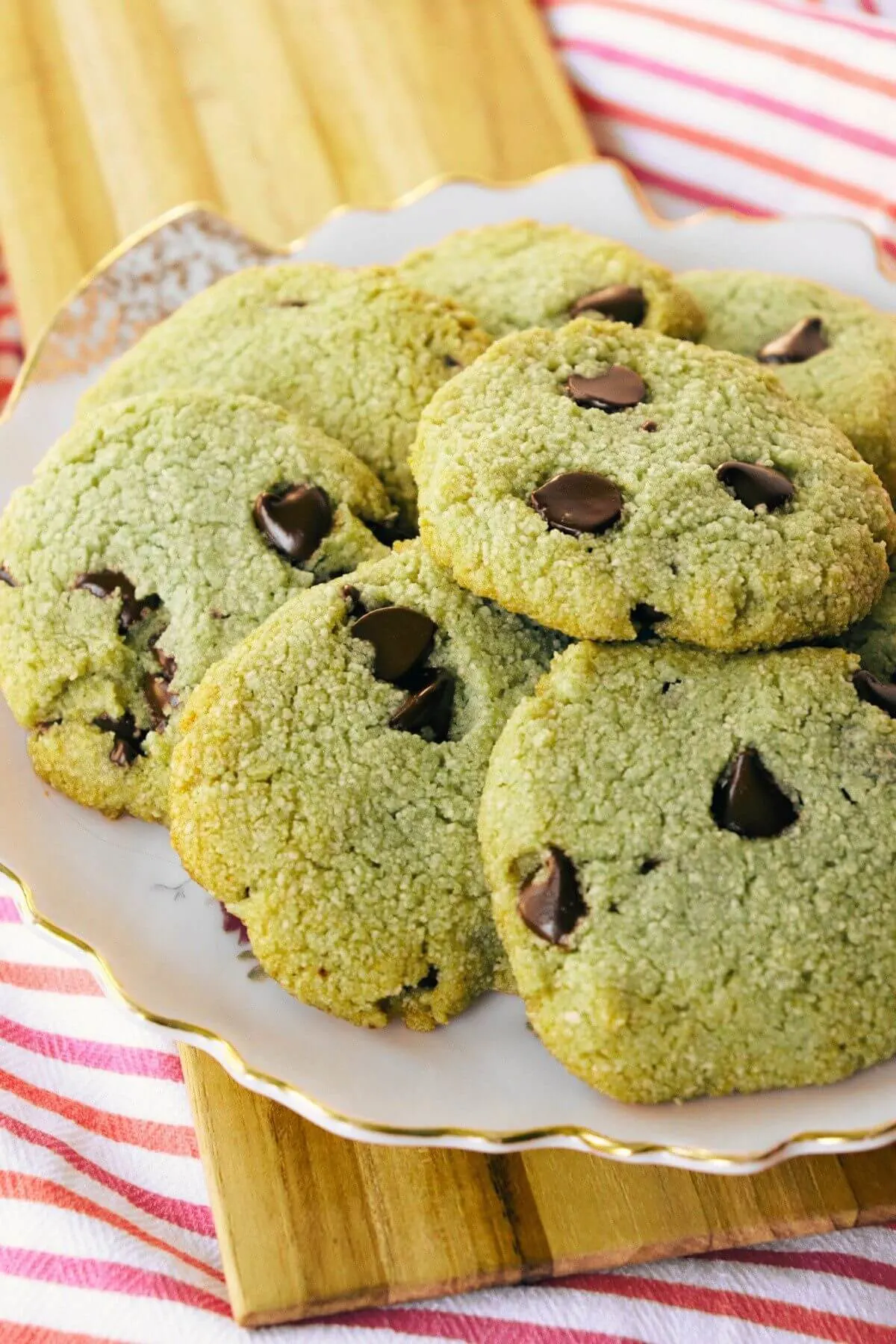 A plate of gluten free matcha cookies sitting on a wooden board