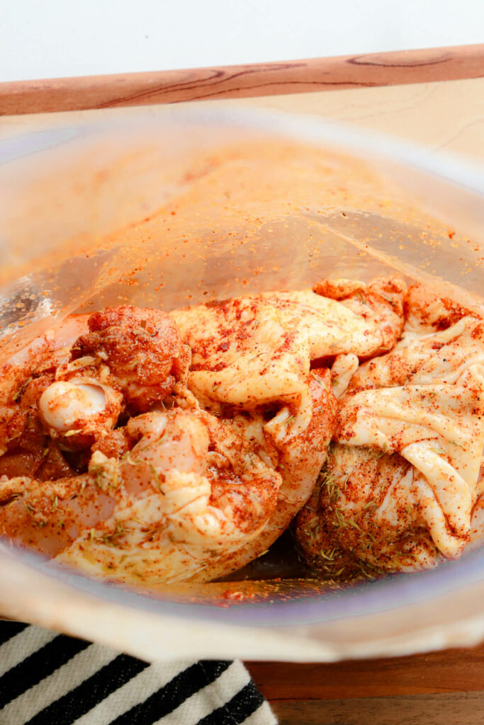 Chicken thighs in a zipper bag mixed with olive oil and seasoning