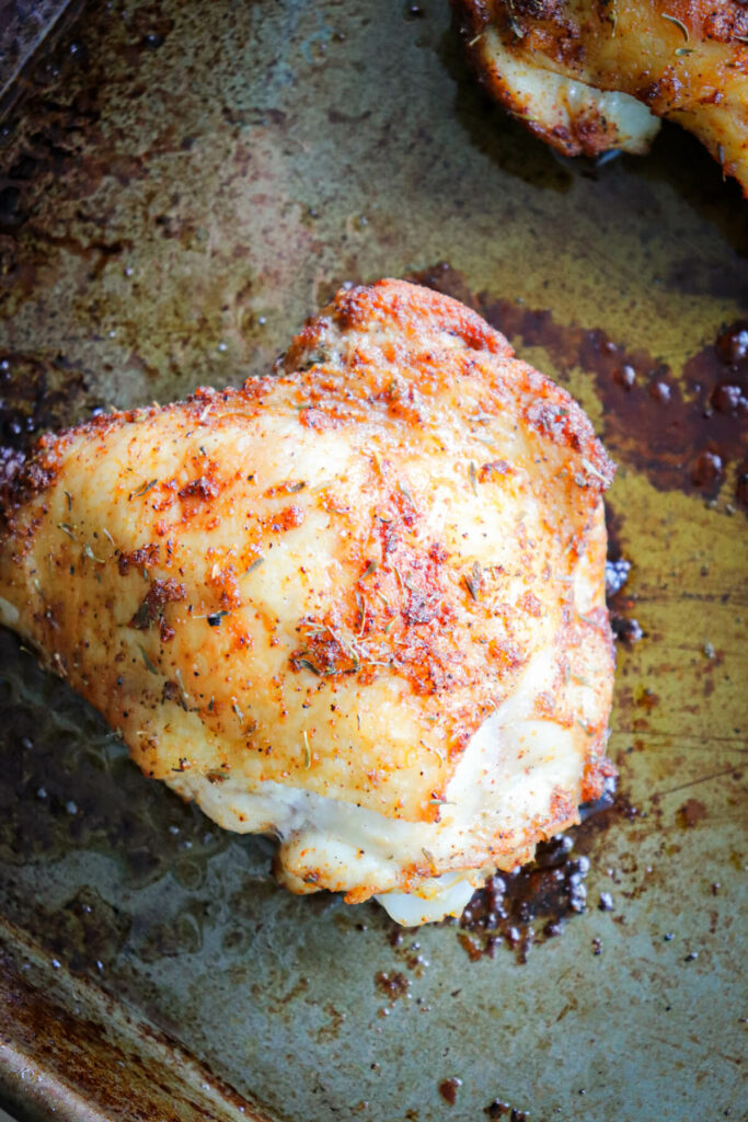 Overhead view of view of an oven baked chicken thigh on a baking pan